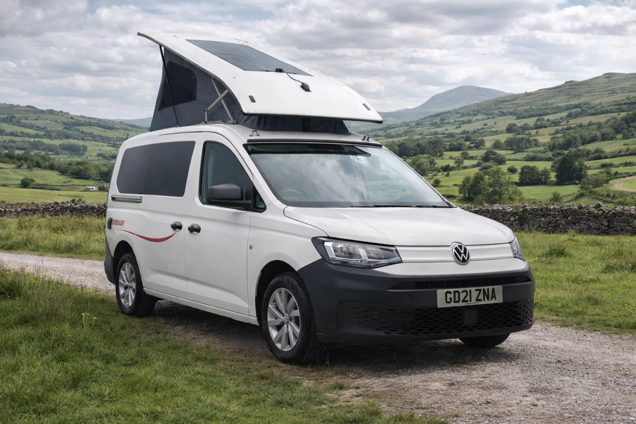 White Volkswagen camper van with pop-up roof in countryside